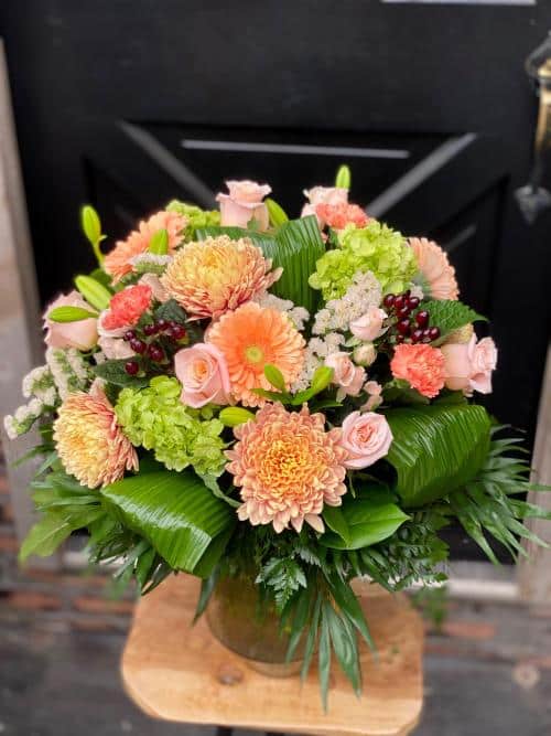 The Watering Can | A large orange and pink bouquet in a glass vase.