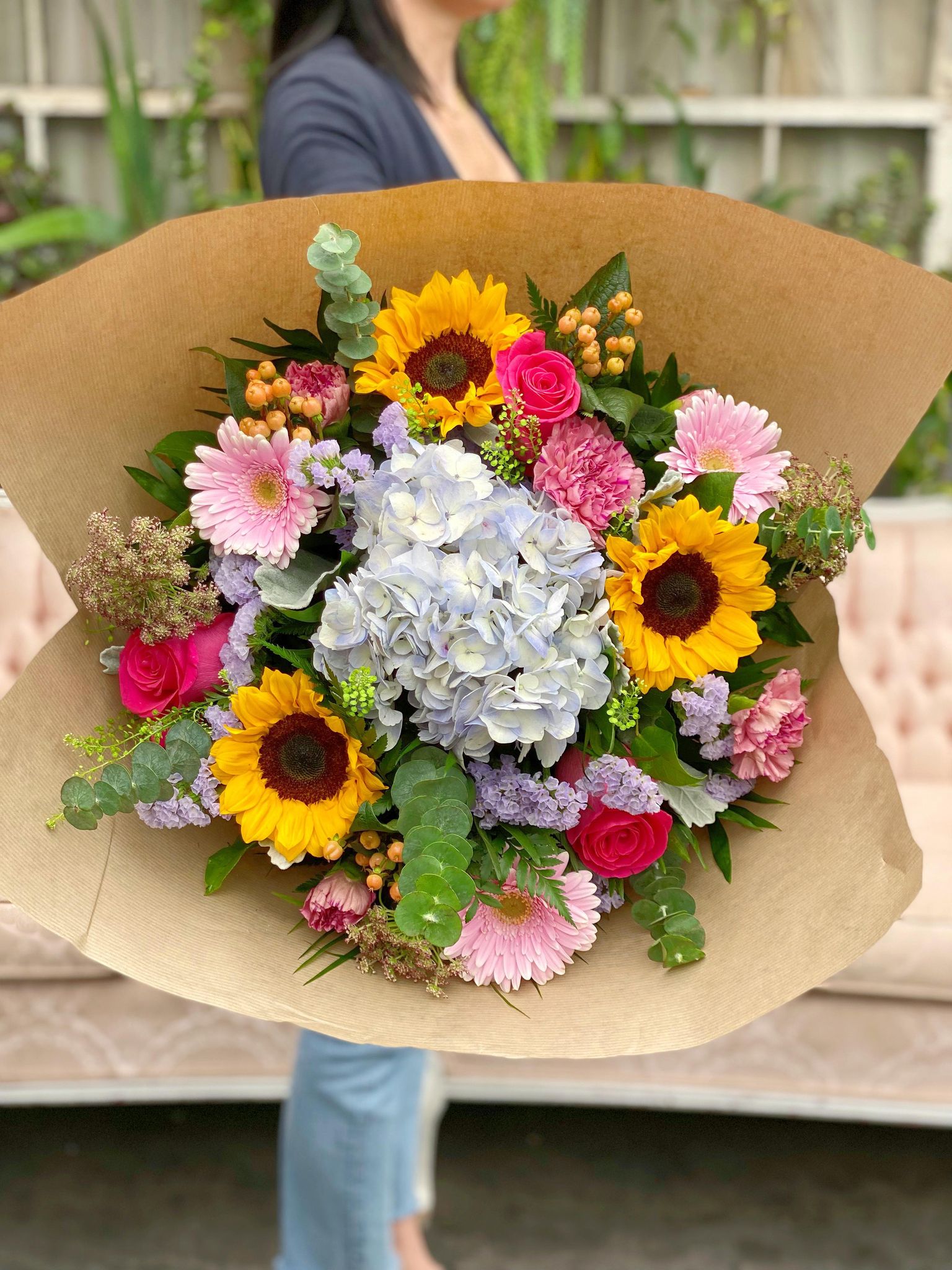 The Watering Can | A lage gardeny hand-tied bouquet with lavender hydranea, sunflowers, roses, and gerberas.
