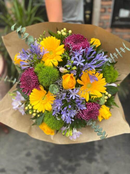 The Watering Can | A stunning hand-tied bouquet in blues, yellows, and plums.