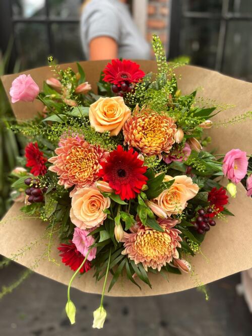 The Watering Can | A large handtied bouet in red, orange, peach , and pink colours.