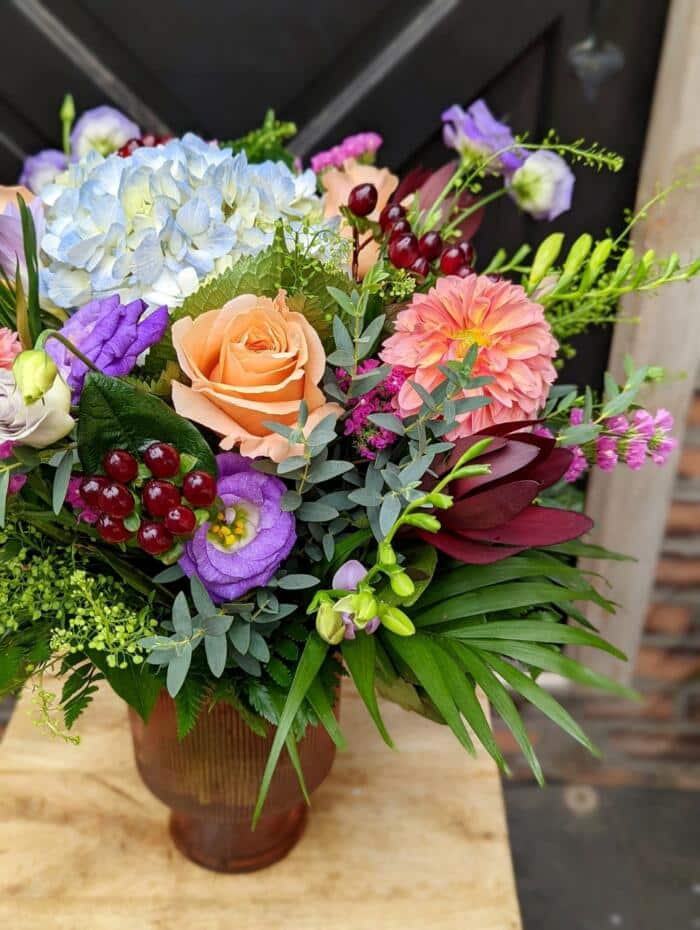 The Watering Can | A large colourful bouquet in a mahogany coloured glass pedestal vase.
