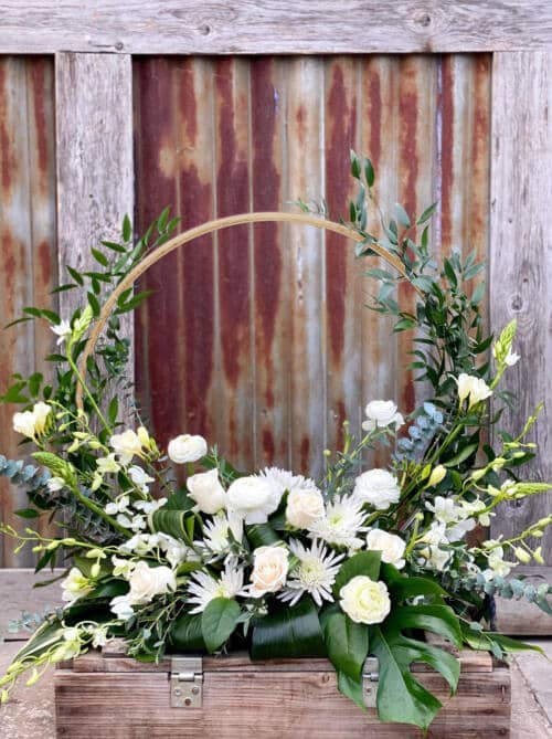 The Watering Can | A large European style arrangement using white flowers arranged upwards along a gold hoop.