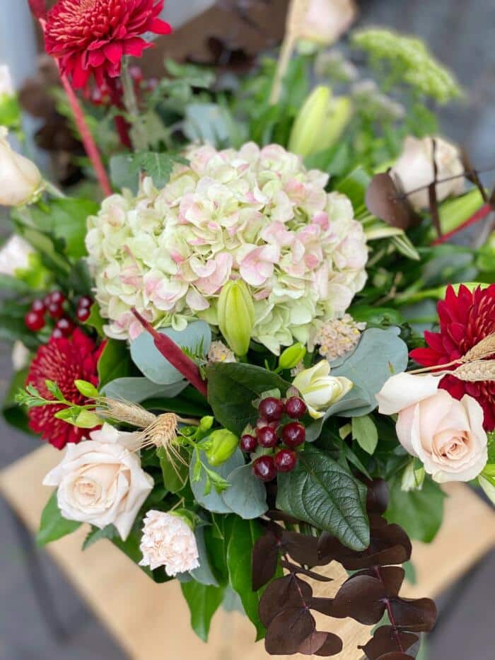 The Watering Can | Close up of an antique hyrangea alongside other blush and burgundy blooms in a large bouquet.