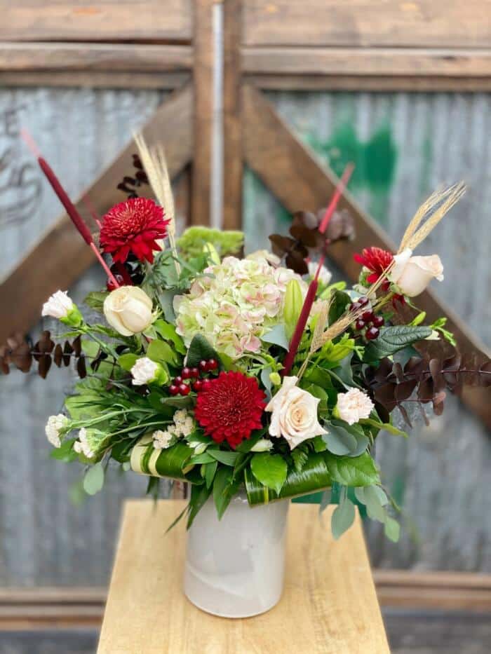 The Watering Can | A large blush and burgundy bouquet in a tall beige ceramic vase.