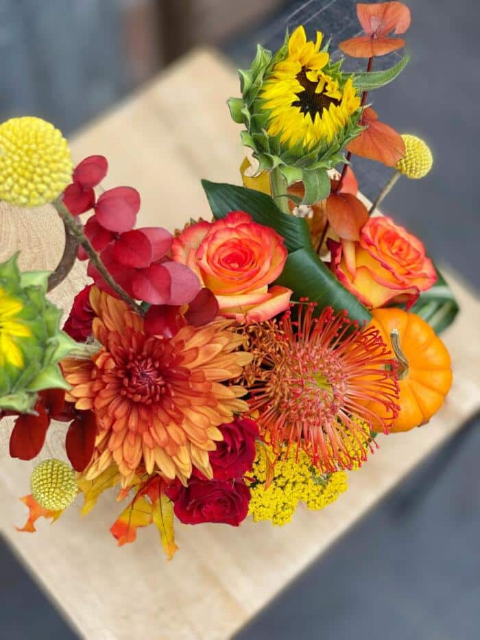 The Watering Can | Top down view of a fall European arrangement of orange and yellow flowers.
