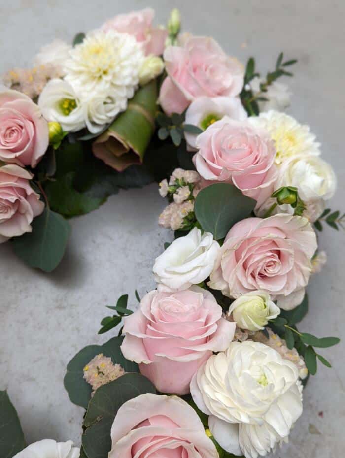 The Watering Can | A close up of soft pink roses, white lisianthus, white rununculus, and blush statice in a open heart design.