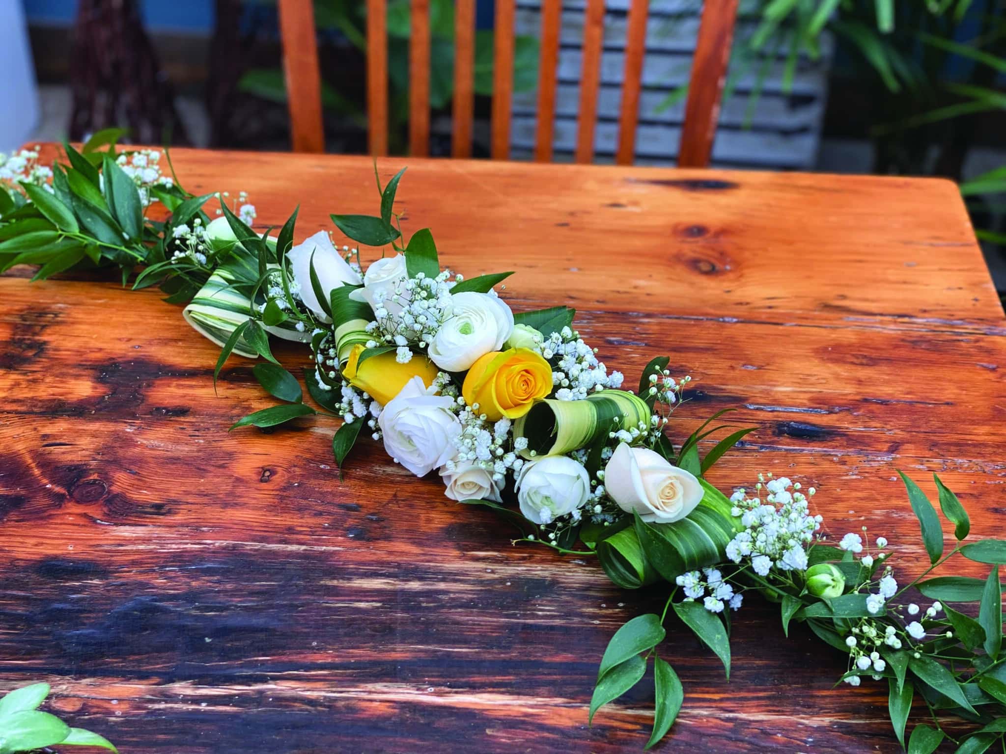 The Watering Can | A garland of white roses, yellow roses, white rununculus, baby's breath, aspidestra, and ruscus.