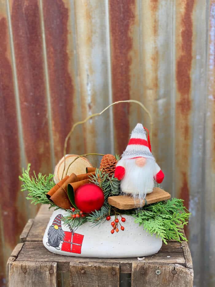 The Watering Can | A festive arrangement in a white oval container and a gnome stuffy amongst the greens.