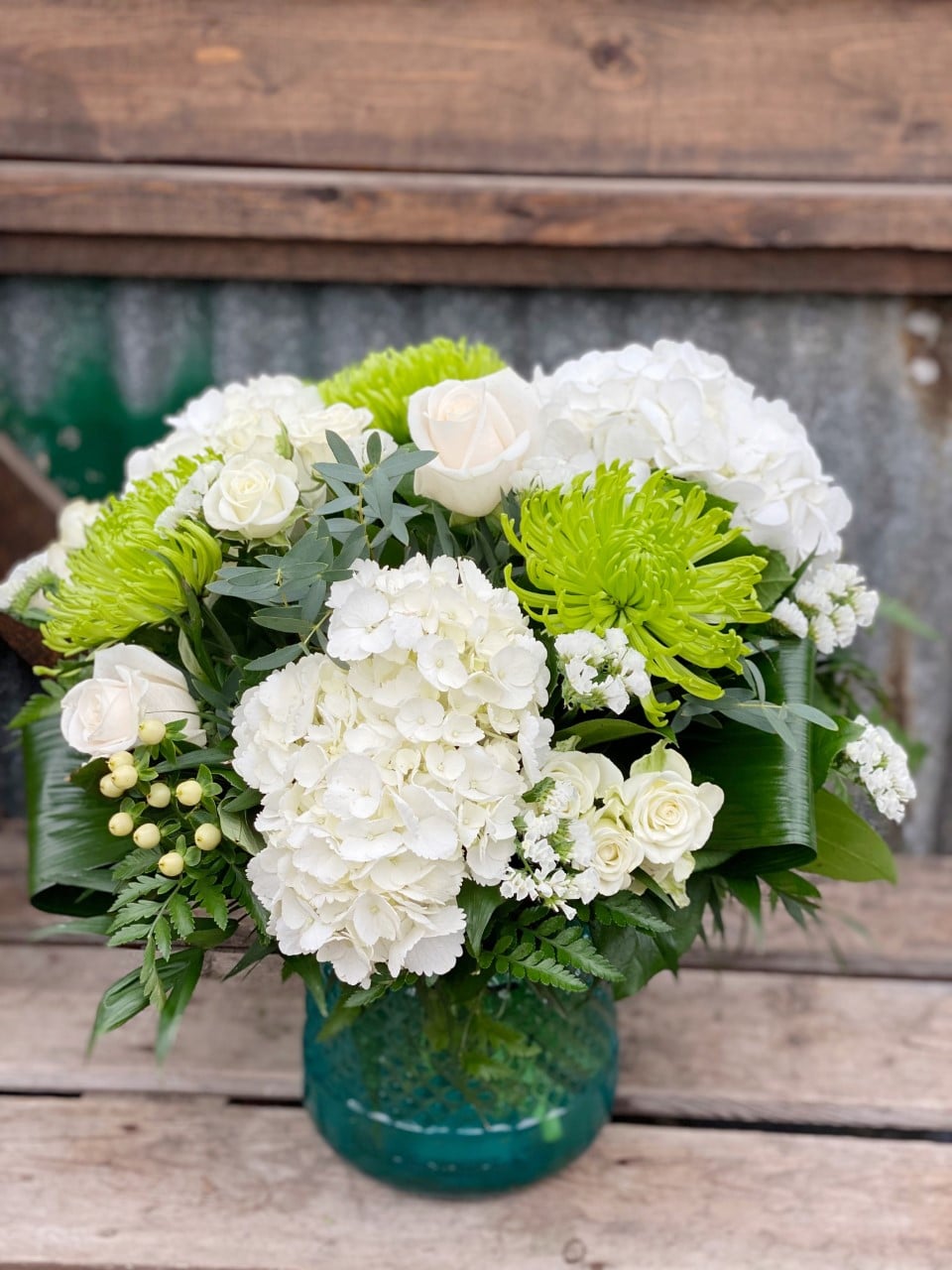 The Watering Can | A large green and white bouquet in a blue textured glass vase.