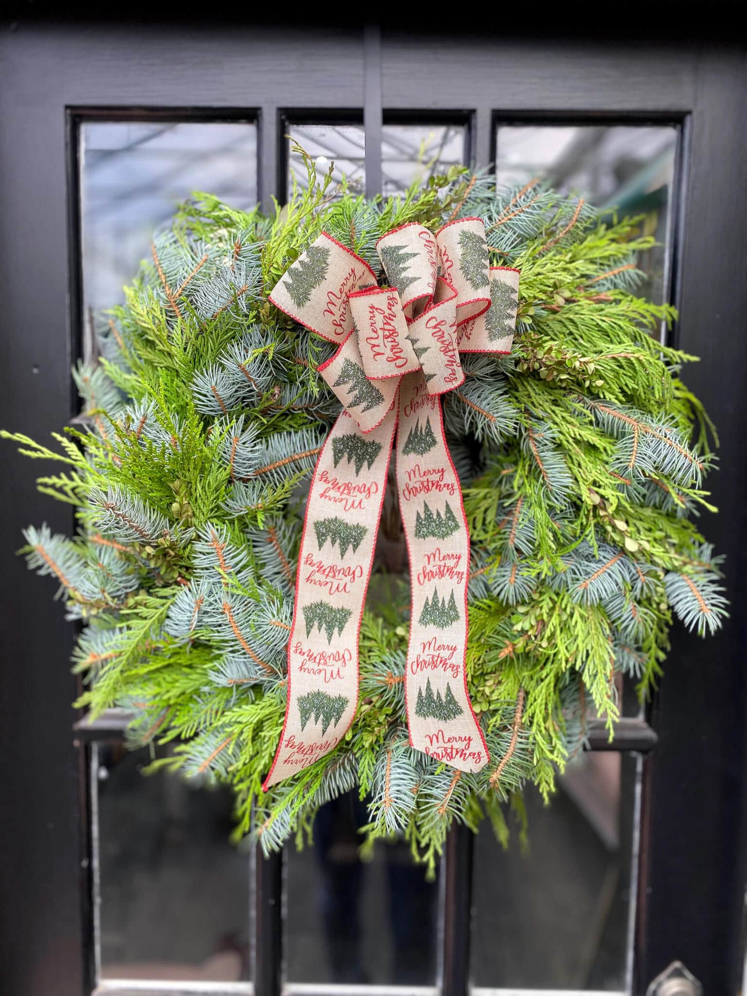 The Watering Can | Large wreath of evergreens with a large bow.
