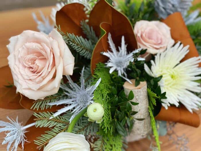 The Watering Can | Close up of the blush roses and white thistle in a European style arrangement.