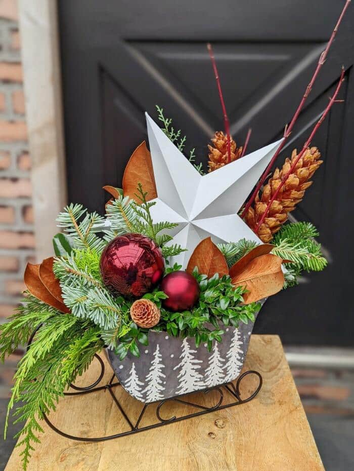 The Watering Can | A festive winter arrangement designed in a silver tinsleight with a white tree design on it.